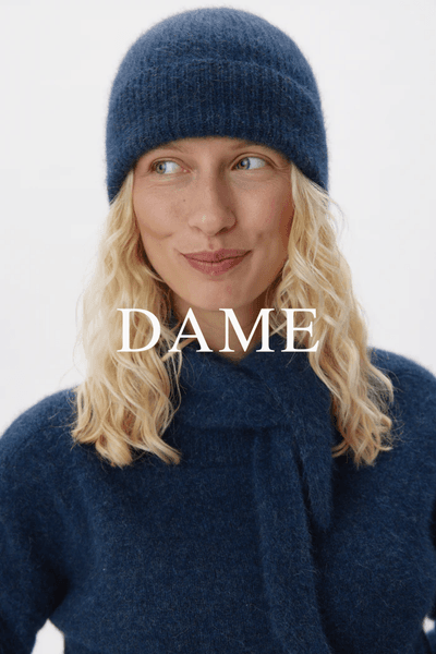 Dame banner med modell iført lue og strikkegenser fra Six Ames mot lys bakgrunn