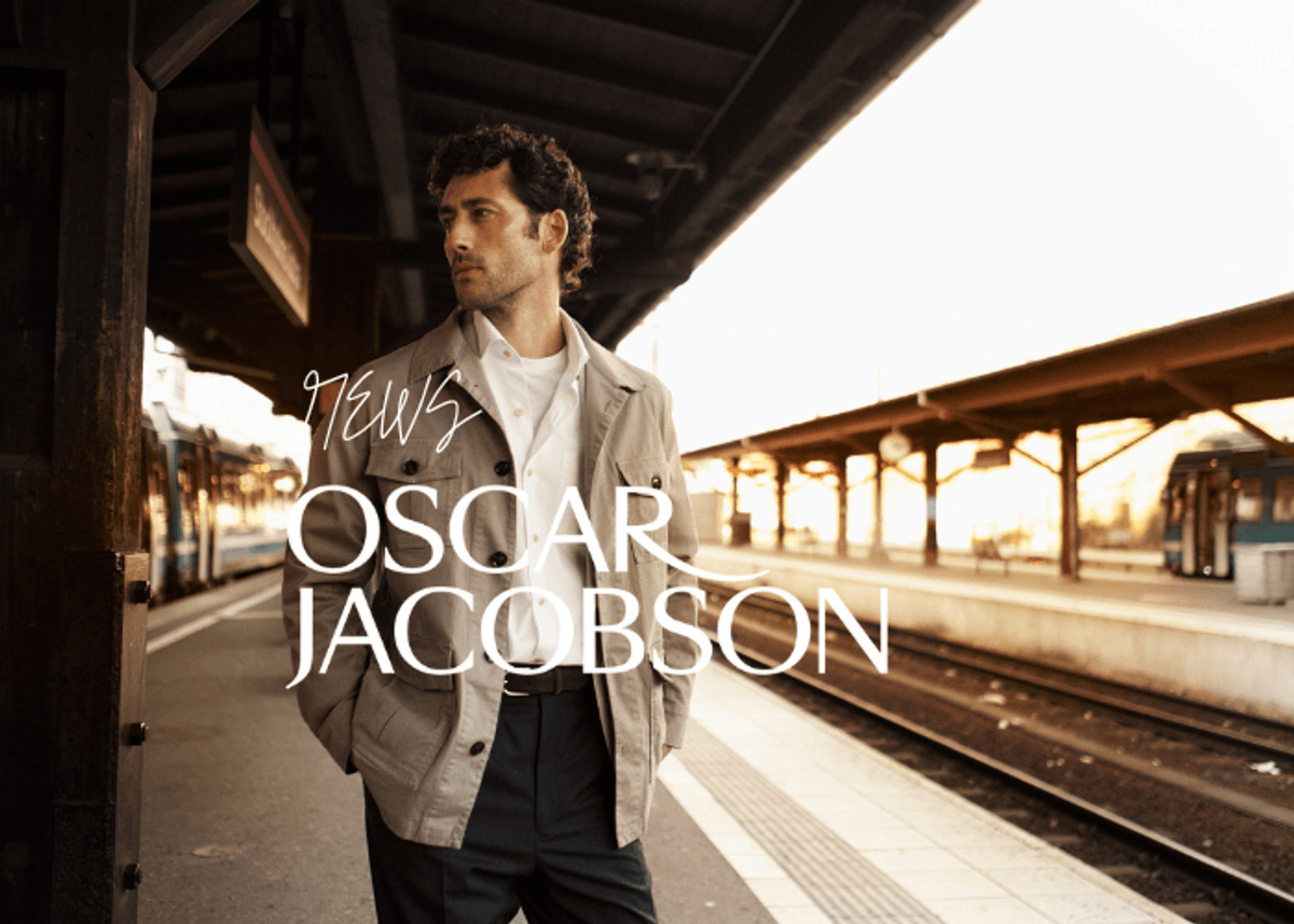 Herremodell i lys jakke og hvit skjorte fra Oscar Jacobson fotografert på togstasjon